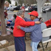 Two older women hugging at a community event